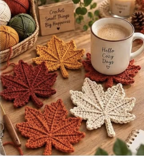 Crocheted maple leaf coasters in autumn colors arranged on a wooden table with a cozy mug.