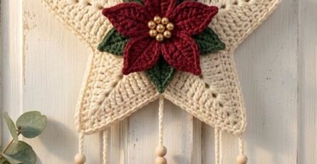 A festive crochet wall hanging with a cream star, red poinsettia, green leaves, hanging trees, heart, bells, and a red ribbon bow.