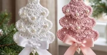 Two crocheted Christmas tree ornaments, one white and one pink, decorated with pearls and bows, hanging side by side.