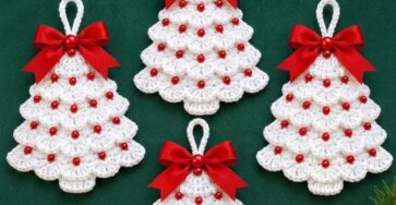 Four white crochet Christmas tree ornaments with scalloped layers, red beads, and red ribbon bows, arranged on a green background.