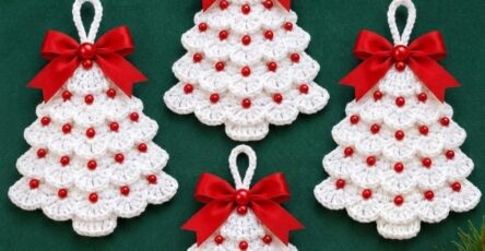 Four white crochet Christmas tree ornaments with scalloped layers, red beads, and red ribbon bows, arranged on a green background.