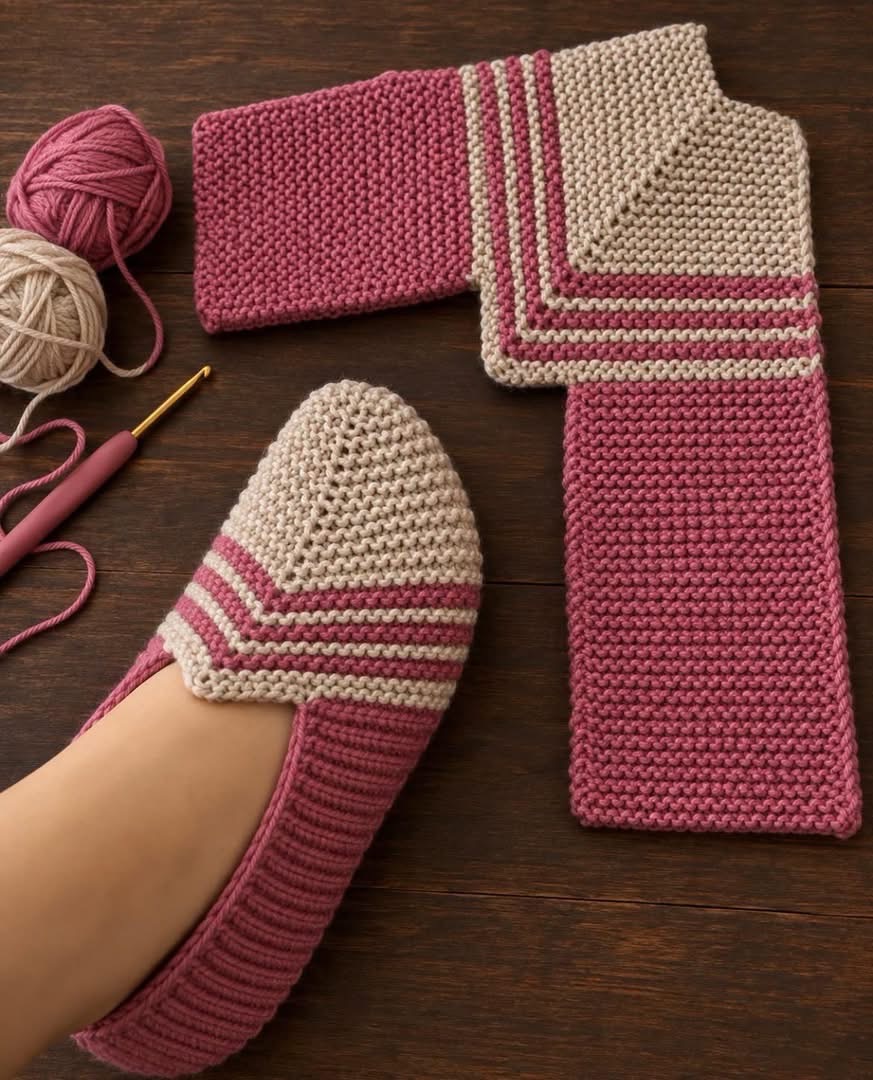 A pair of handmade crochet slippers, one slipper on a foot, the other flat with visible construction in pink and beige yarn.
