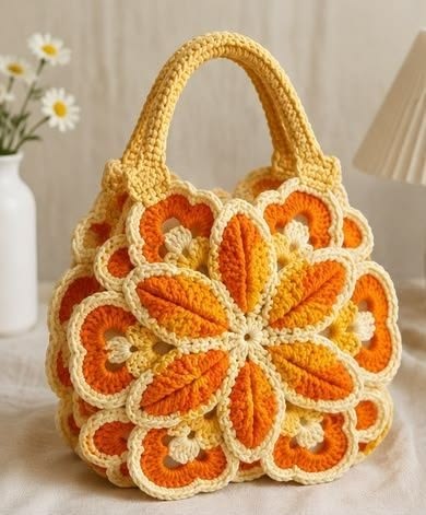 A colorful crochet handbag with yellow and orange flower motifs, joined together and finished with sturdy handles.