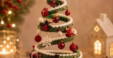 A spiral-shaped crochet Christmas tree ornament, decorated with small crochet baubles, mini presents, a yellow star topper, and a red hanging loop.