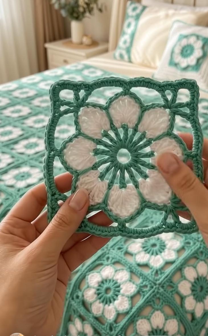 Lacy crochet granny square motif with a white flower center and green openwork border, used in a bedspread and pillow.