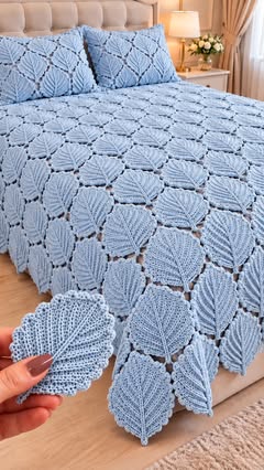 Light blue crochet bedspread with closely joined leaf motifs, displayed on a bed with matching pillow shams.