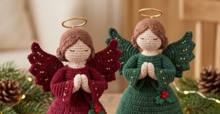 Two crocheted angel figurines with scalloped dresses, praying hands, wings, golden halos, and holly embellishments in burgundy and green.
