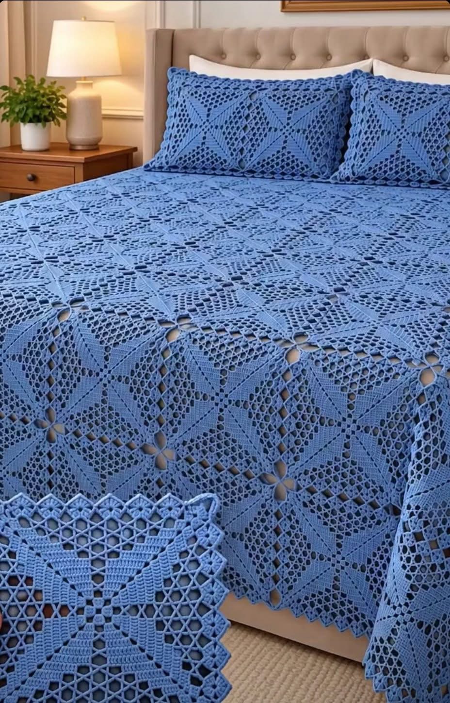 A blue crochet bedspread and matching pillow covers made with intricate lace square motifs, displayed on a neatly made bed.