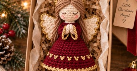 A handmade crochet Christmas angel ornament in a gift box with festive decorations around.