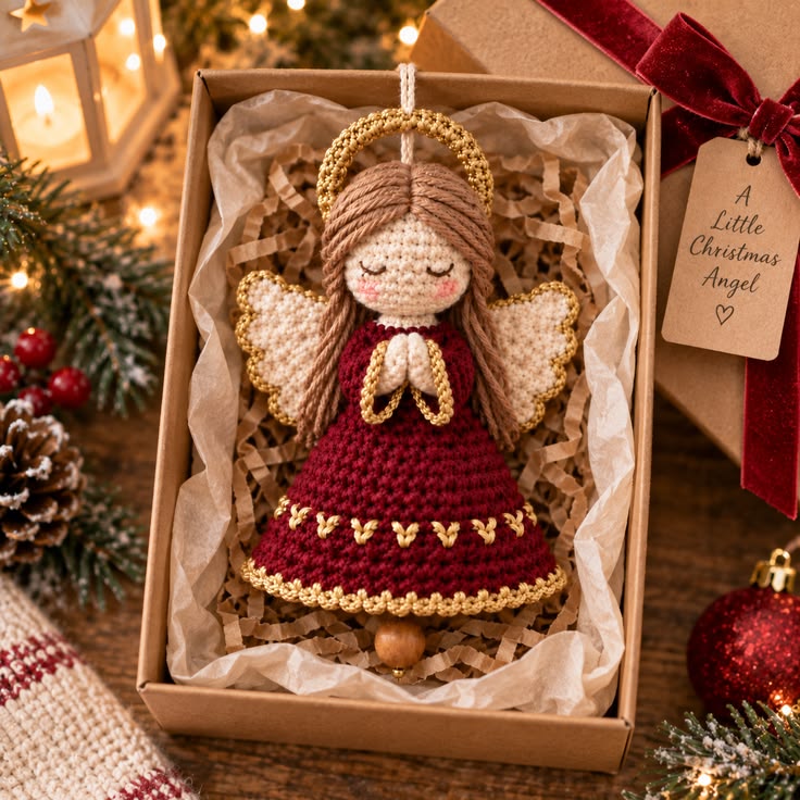 A handmade crochet Christmas angel ornament in a gift box with festive decorations around.