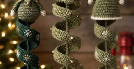 Three green crochet Christmas tree ornaments: an elf, a tree, and an angel with spiral bases and bells, hanging on a festive branch.