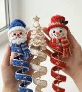 Three spiral crochet Christmas ornaments: a blue Santa, a white and gold Christmas tree, and a red snowman, each held by hand.