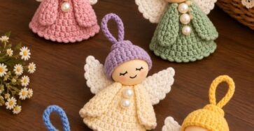 Five cute crochet angel ornaments in various pastel colors with wings, round heads, and pearl buttons, arranged on a wooden table.