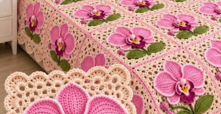 A crochet blanket and pillows made from square motifs with 3D pink orchid flowers and green leaves on a lacy cream background.