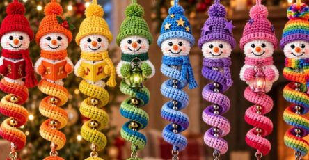 A set of colorful crochet spiral snowman ornaments, each with a different color and festive details, hanging on a branch with holiday decorations in the background.