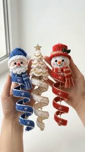 Three crocheted Christmas ornaments: a blue Santa, white Christmas tree, and red snowman, each with a spiral body.