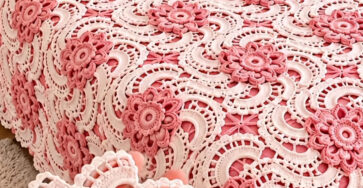 Elegant crochet bedspread and pillow covers made of joined pink and white floral motifs in a vintage lacy pattern.