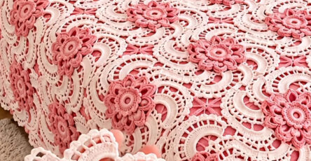 Elegant crochet bedspread and pillow covers made of joined pink and white floral motifs in a vintage lacy pattern.