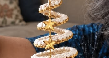 A hand-crocheted spiral Christmas tree ornament with a central gold string, golden star charms, and a crocheted star topper, featuring white textured stitches bordered in gold.