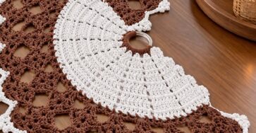 A long, decorative crochet table runner featuring spiral fan motifs in white and brown with a lacy geometric openwork pattern and scalloped edging.