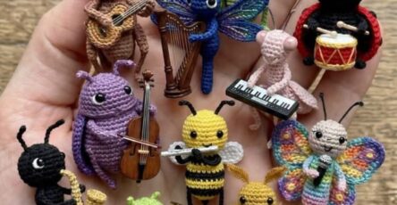 A hand holding a collection of tiny, crocheted amigurumi insects, each playing a miniature musical instrument.