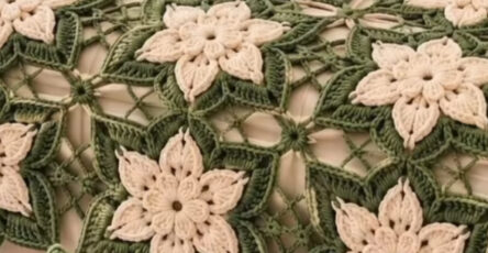 A crochet bedspread and pillow set featuring cream and green star-shaped flower motifs joined in a lacy design.