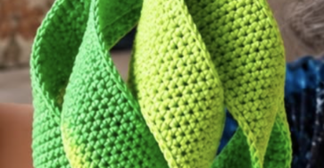 Vibrant crochet geometric hanging ornament made of layered green leaf-like shapes with beaded top.