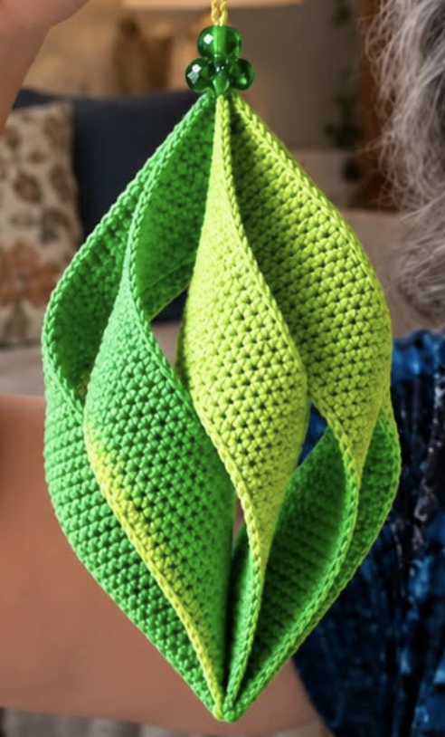 Vibrant crochet geometric hanging ornament made of layered green leaf-like shapes with beaded top.