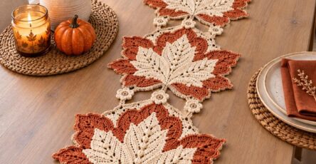 Crochet table runner with layered maple leaf motifs in beige and rust, connected with small flower motifs, displayed on a wooden table.