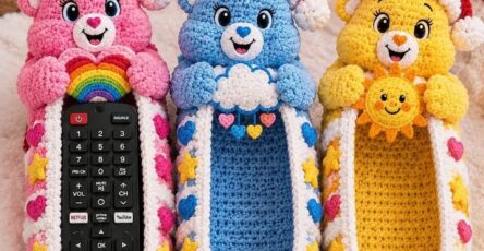 Three crocheted Care Bear-inspired remote holders with pink, blue, and yellow bears, each featuring 3D arms, ears, Santa hats, and iconic belly motifs.
