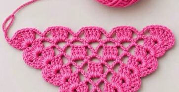 A vibrant pink crochet triangle motif worked in cluster stitches, with a matching yarn ball.