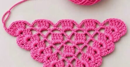 A vibrant pink crochet triangle motif worked in cluster stitches, with a matching yarn ball.