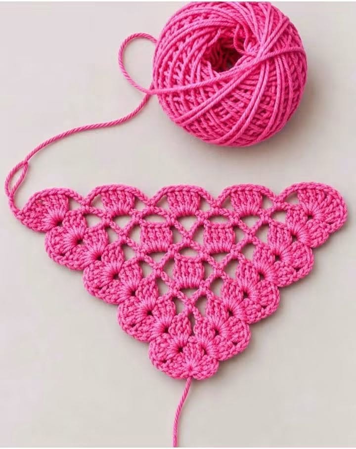 A vibrant pink crochet triangle motif worked in cluster stitches, with a matching yarn ball.
