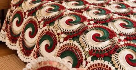 A crochet Christmas-themed bedspread and pillow set featuring large circular swirl motifs in red, green, and white with decorative edges.