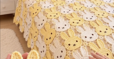 A cozy bed draped with a crochet blanket made of yellow and white bunny face motifs, with crocheted bunny faces shown in hand.