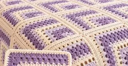 Lavender and cream log cabin granny square crochet blanket on a bed with matching pillows in a cozy bedroom.