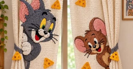 Hand-crocheted curtains with a cartoon cat, mouse, and yellow cheese applique designs, suitable for a playful kids' room decor.