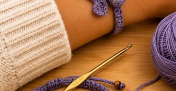 A lavender crochet bracelet shaped like a dragon with gold bead details, shown worn on a wrist and laid flat beside a crochet hook and yarn.