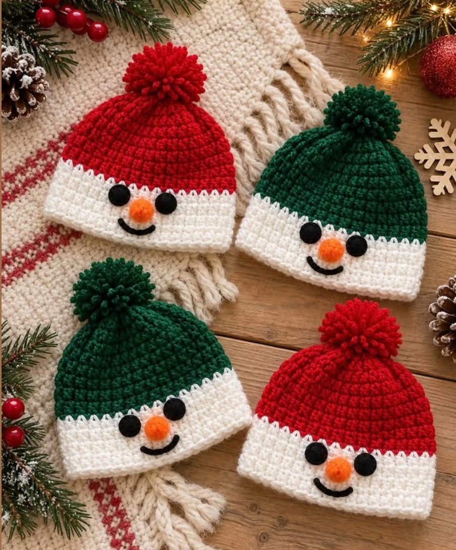 Four crochet snowman beanie hats with red or green tops, white lower halves, pom poms, smiles, and cute faces, on a rustic wooden surface.