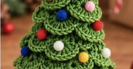 A crocheted 3D Christmas tree with layered green branches, a yellow star on top, and multicolored small round decorations.