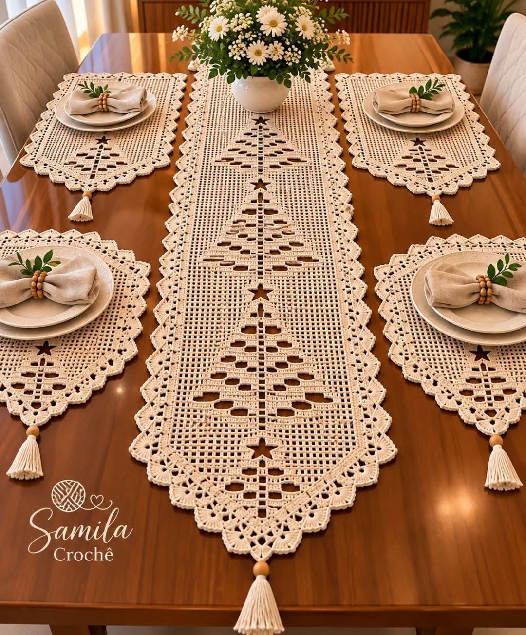 A beige crochet table runner and four matching placemats with tree motifs and scalloped edges, each adorned with tassels, displayed on a wooden table.