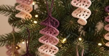 Several spiral crochet tree ornaments in ombre shades of purple and cream, hanging on a Christmas tree.