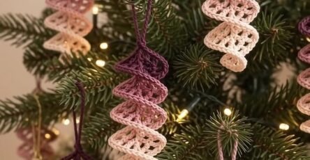 Several spiral crochet tree ornaments in ombre shades of purple and cream, hanging on a Christmas tree.