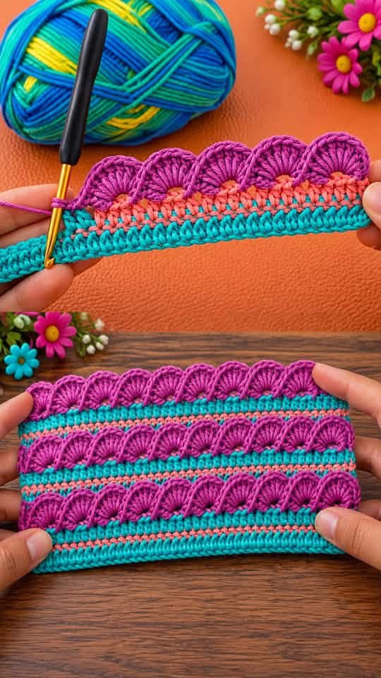 A crocheted rectangular panel with repeating shell stitch stripes in bright purple, aqua, and peach yarn.