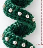 A crochet ornament shaped like a spiral Christmas tree, decorated with beads, a metallic star at the top, and a bell at the bottom.
