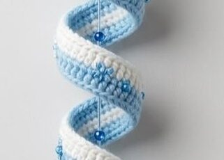 A crocheted hanging ornament of a penguin head with hat and a long, blue and white spiral tail decorated with beads and snowflake embellishments.