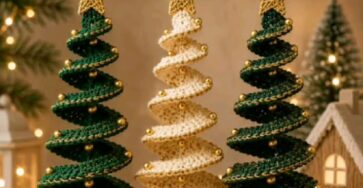 Three spiral crochet Christmas tree ornaments in green and cream with gold bead accents and star toppers hanging from a branch.