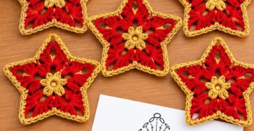 Six crocheted red and gold star motifs with an openwork design, ideal for coasters or festive decoration, displayed on a wooden table.