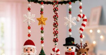 A colorful crochet Christmas mobile with Santa, snowman, reindeer, Christmas tree, candy canes, snowflakes, and stars hanging from a decorated circular frame.