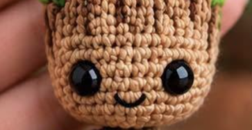 A crocheted amigurumi tree doll keychain with brown body, green leaf accents, and large black safety eyes.